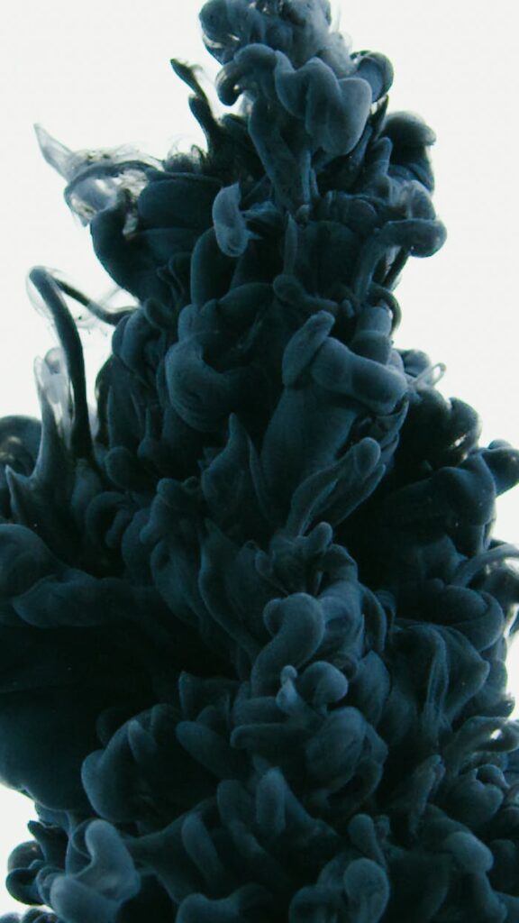 Close-up of black ink swirling in water, creating an abstract and fluid design.